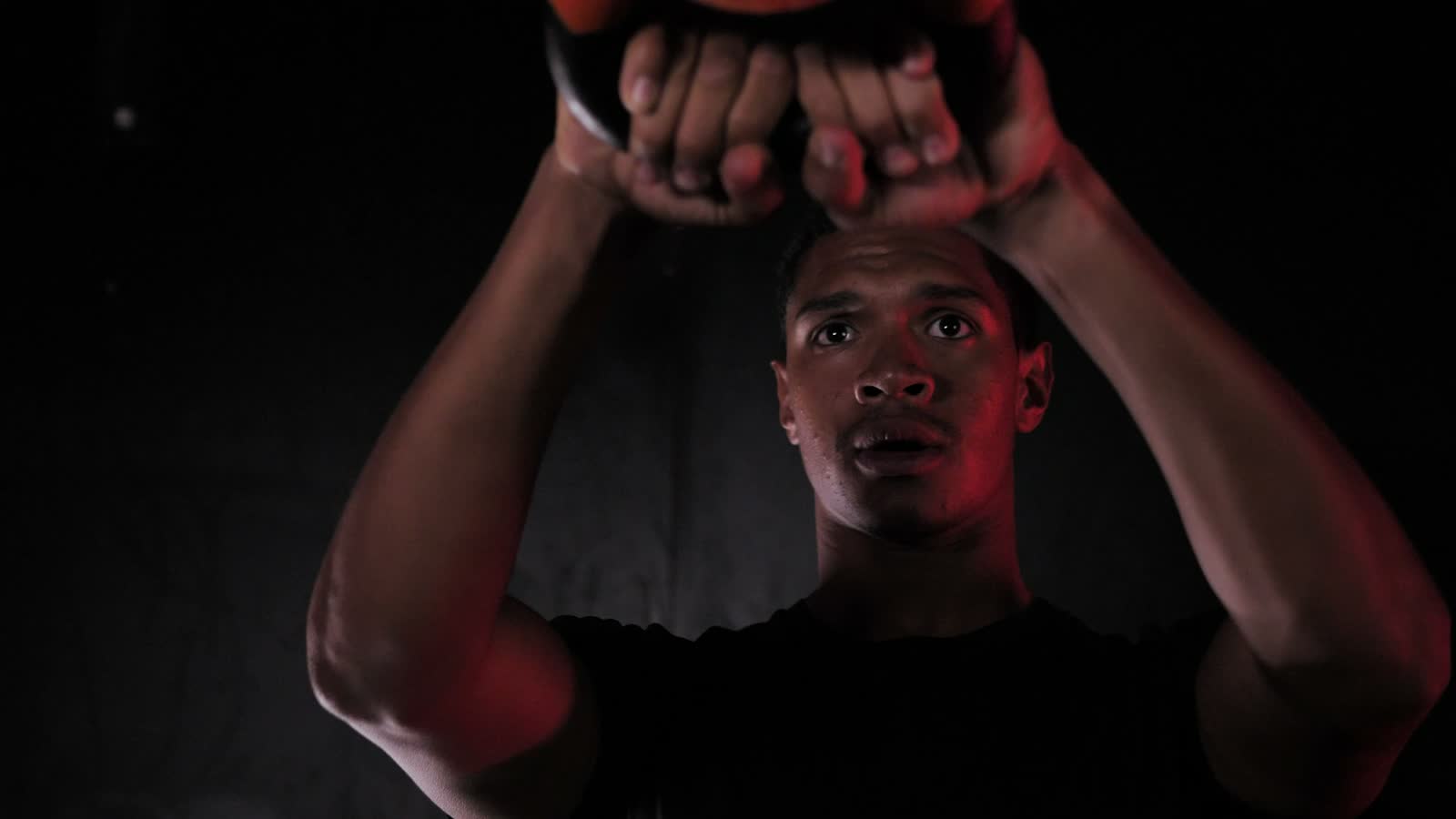 Un atleta solleva un kettlebell sopra la testa in un box di cross training