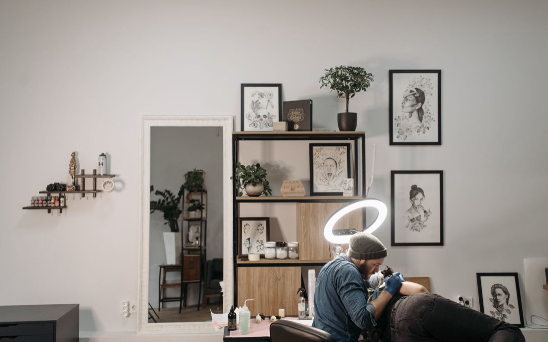 Uno studio di tatuaggi con le tavole appese alle pareti e una seduta in corso